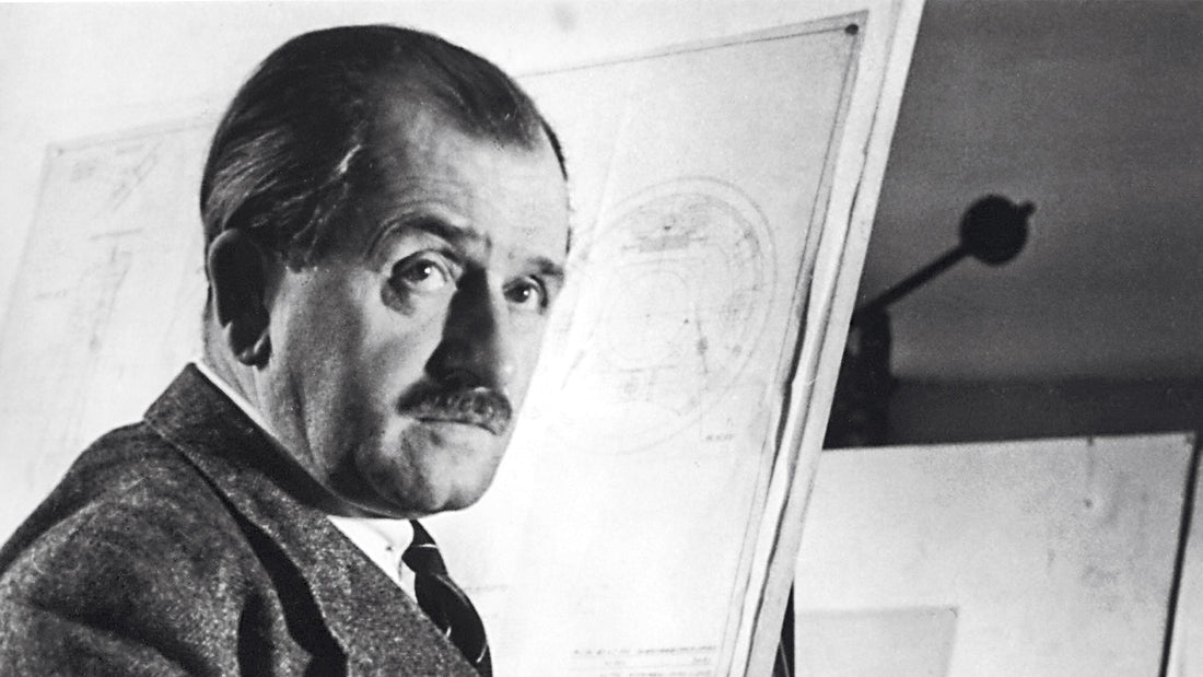 Portrait of an older Ferdinand Porsche in front of an engineer drawing board