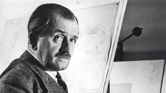 Portrait of an older Ferdinand Porsche in front of an engineer drawing board